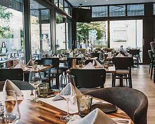 Ristorante elegante con tavoli apparecchiati e vista esterna.