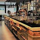 Innenansicht einer stilvollen Bar mit Holztheke und Gläsern.