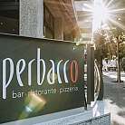 Schild des Restaurants Perbacco mit Sonnenstrahlen im Hintergrund.