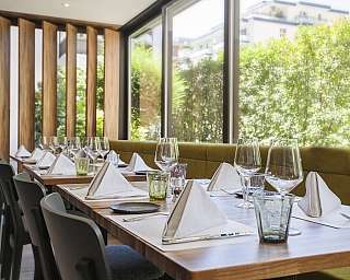 Tavoli apparecchiati con bicchieri e tovaglioli in un ristorante moderno.