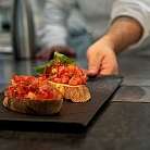 Zwei Bruschetta mit Tomaten und Basilikum auf schwarzem Teller.
