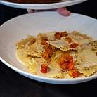 Ein Teller Ravioli mit cremiger Sauce und buntem Gemüse.