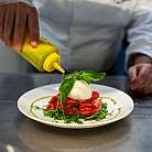 Ein Koch dekoriert einen Salat mit Tomaten und Mozzarella.