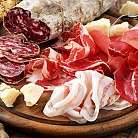 Vielfalt an Wurstsorten und Käse auf einem Holzbrett.