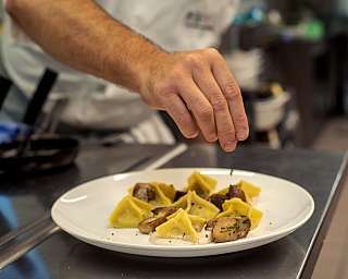Uno chef aggiunge un tocco finale a un piatto di ravioli.