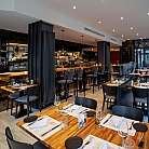 Elegantes Restaurant mit Holzstühlen und Tischen, gut beleuchtet.
